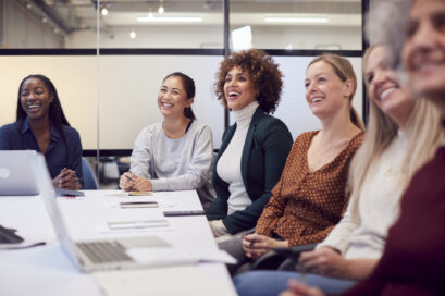 Line Of Businesswomen In Modern Office Listening To Presentation By Colleague Line Of Businesswomen In Modern Office Listening To Presentation By Colleague